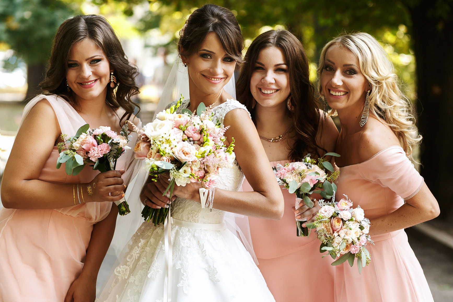 Smiling bride and bridesmaids in pink dresses outside